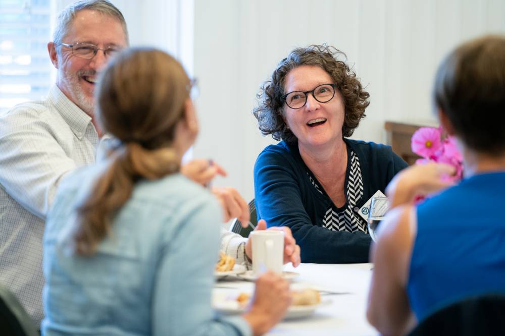 Faculty members laugh together at a table